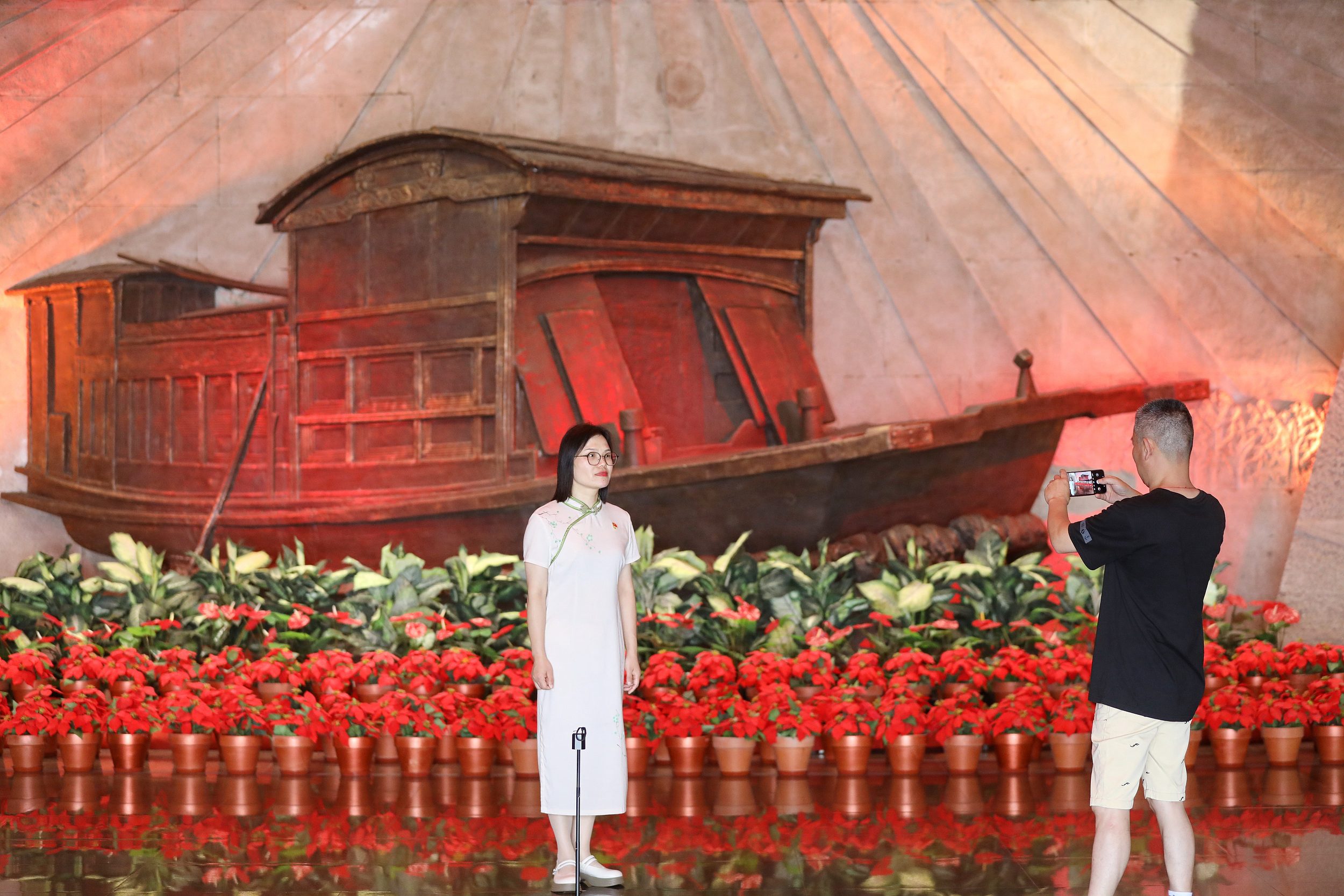 2025年6月24日，浙江嘉興，游客在南湖革命紀(jì)念館與紅船雕塑合影。（圖片來(lái)源：視覺(jué)中國(guó)）